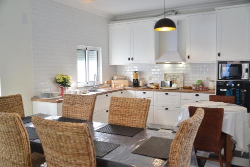 a kitchen with a table and chairs and a kitchen with white cabinets at Blue Castle House in Gouveia