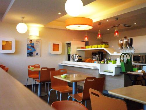 a restaurant with tables and chairs and a kitchen at ibis budget Montauban Les Chaumes in Montauban