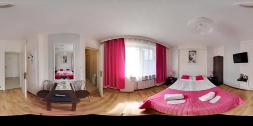 Gościniec Margo في جانكي: غرفة نوم كبيرة مع سرير وردي وطاولة