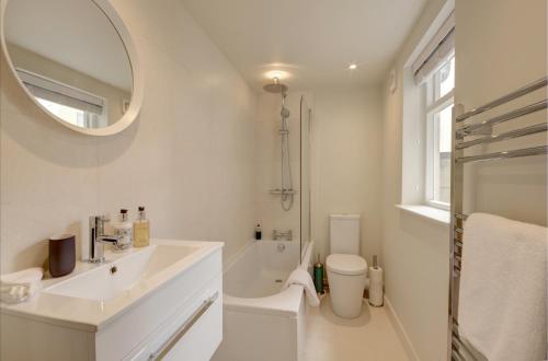 a white bathroom with a sink and a mirror at Stunning Montpellier Spa Road apartment in Cheltenham