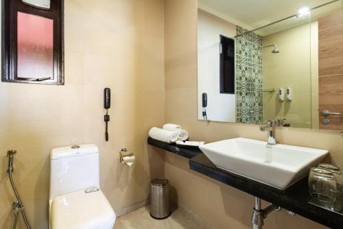 a bathroom with a sink and a toilet and a mirror at Somy Plaza Calangute Goa - Formerly Somy Resort in Calangute