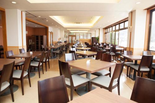 un restaurante con mesas y sillas de madera y ventanas en Hotel Route-Inn Kawaguchiko en Fujikawaguchiko