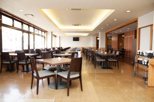 a dining room with tables and chairs and windows at Hotel Route-Inn Kawaguchiko in Fujikawaguchiko