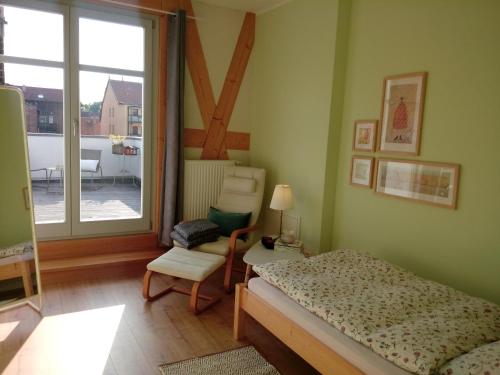 a bedroom with a bed and a chair and a window at Ferienwohnung Linsenstrasse 13 in Mühlhausen