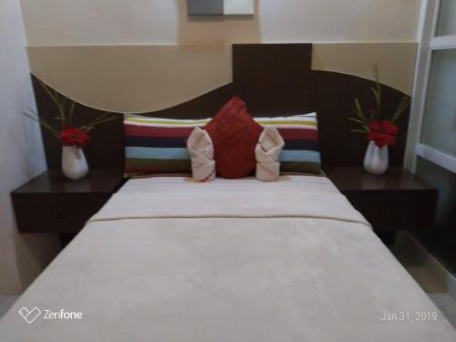 a bed in a room with two vases at HappyNest 1857 @ Cityland Tagaytay in Tagaytay
