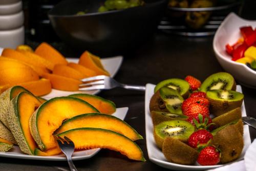 two plates of fruit on a table with forks and strawberries at SL'otel Budget in Bernburg