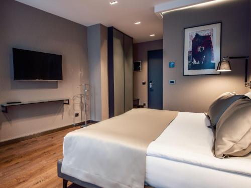 a bedroom with a large white bed and a flat screen tv at Seraphine Plaza in Peje