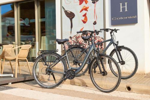 dos bicicletas están estacionadas fuera de una tienda en Hotel Colonial en Colonia Sant Jordi