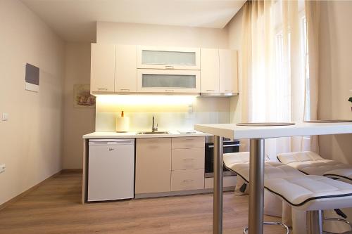uma pequena cozinha com armários brancos e uma mesa em Liston Inn Suites (Piazza) - Heart of Corfu Old Town em Corfu Town