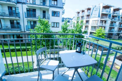 a white table and chairs on a balcony with buildings at Baltic Apartments - Apartamenty Aquamarina in Świnoujście
