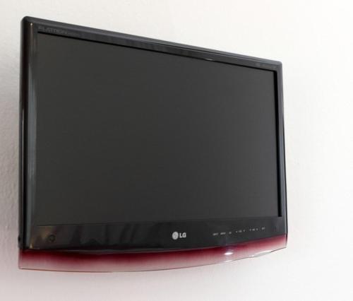 telewizor z płaskim ekranem siedzący na ścianie w obiekcie Noni Rooms w mieście Agia Triada