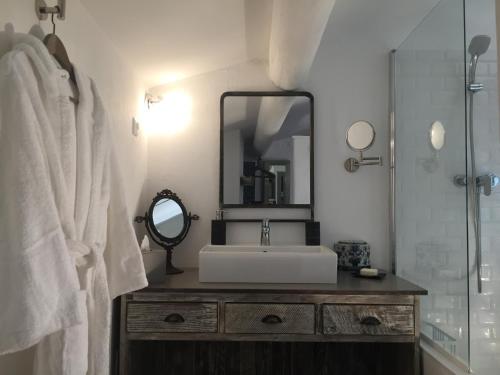 une salle de bain avec un lavabo et un miroir dans l'établissement La Fontaine des Oliviers, à Blauzac