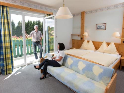 a woman sitting on a couch in a hotel room at Café-Pension Kristall in Harbach