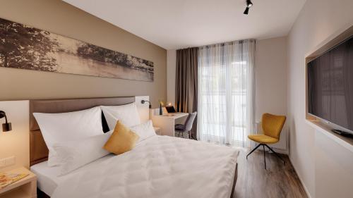 a bedroom with a large white bed and a desk at Amper Art Hotel in Fürstenfeldbruck