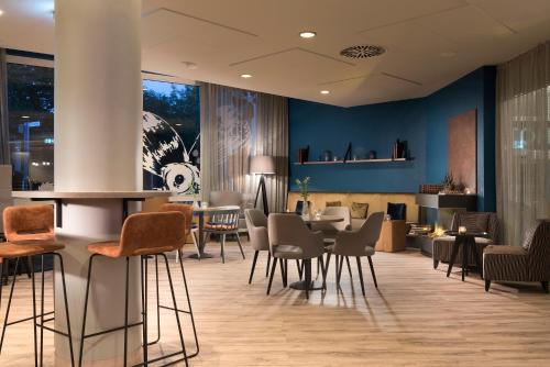a lobby with chairs and tables in a building at Ramada by Wyndham Flensburg City in Flensburg