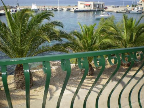 a balcony with palm trees and a body of water at Apartment Smil - 30 m from sea in Sućuraj