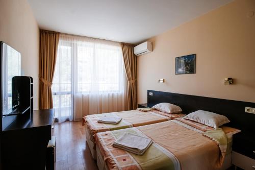 a hotel room with two beds and a television at Red Iguana Hotel in Sveti Vlas