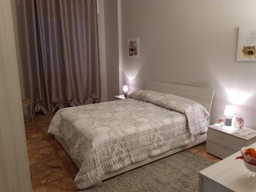 a white bedroom with a bed and two night stands at L'airone apartment in Casale Monferrato