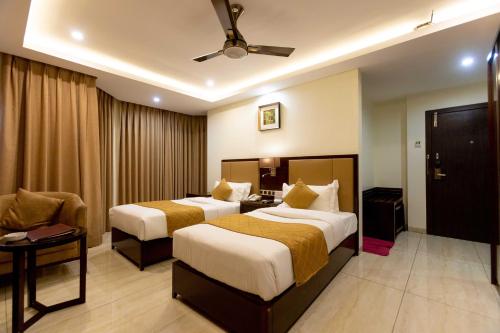 a hotel room with two beds and a couch at Hotel Godwin - Colaba in Mumbai
