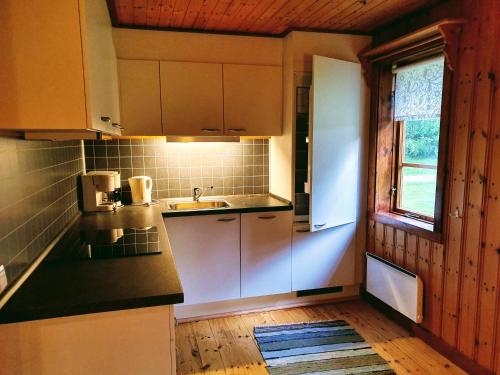 uma cozinha com armários brancos, um lavatório e uma janela em Klarälvsbyn em Sysslebäck
