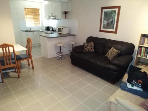 a living room with a black couch and a kitchen at Mandurah Central Estuary Soldiers cove Townhouse in Mandurah