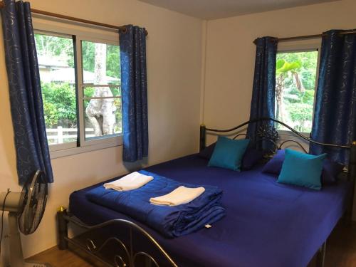ทับศิลารีสอร์ท Tubsila Resort في تشونغ ساداو: غرفة نوم بسرير وملاءات زرقاء ونافذة