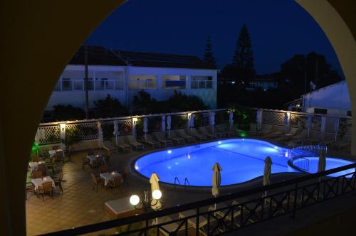 a swimming pool at night with tables and chairs at Konstantina Apartments in Kavos