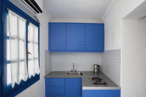 a kitchen with blue cabinets and a sink at Roula Villa Studios & Apartments in Perissa