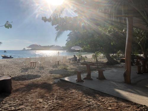 a beach with people sitting on the sand and the ocean at Rim Lay in Ko Kood