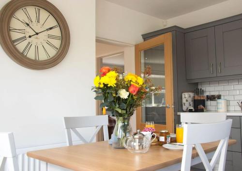 a vase of flowers on a table with a clock at Bramble Cottage in Rathfriland