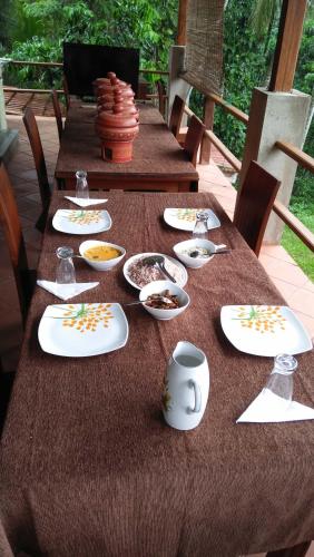 een houten tafel met borden en borden erop bij Ella Residence Eco Resort in Padukka