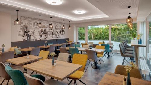 a restaurant with wooden tables and colorful chairs at Amper Art Hotel in Fürstenfeldbruck