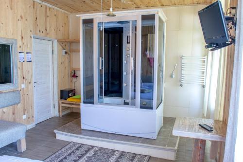 a large glass shower in a room with a tv at Baron Munchausen Guest House in Kamianets-Podilskyi
