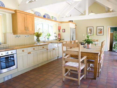 a large kitchen with a wooden table and chairs at Old Barns - Pentre Berw in Llangristiolus