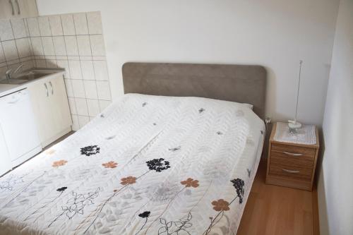 Ce lit se trouve dans une petite chambre dotée d'un couvre-lit avec des fleurs. dans l'établissement Apartment ANGELINA, à Trebinje