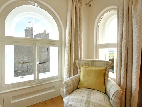 a chair in a room with two windows at Harlech Apartments - Gwern in Harlech