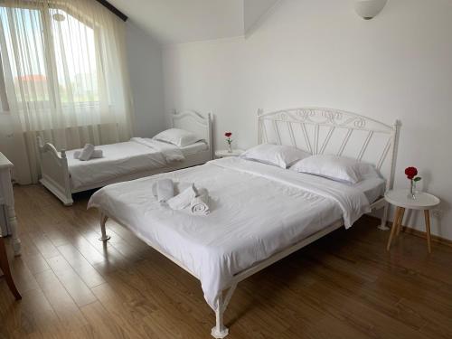 two beds in a bedroom with white sheets and pillows at Vila Ann in Eforie Nord
