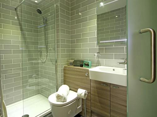 a bathroom with a shower and a toilet and a sink at Harlech Apartments - Gwern in Harlech