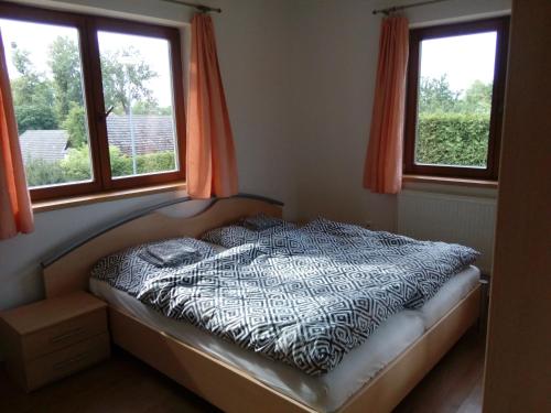 a bed in a bedroom with two windows at Řikovice Prázdninový dům in Morašice