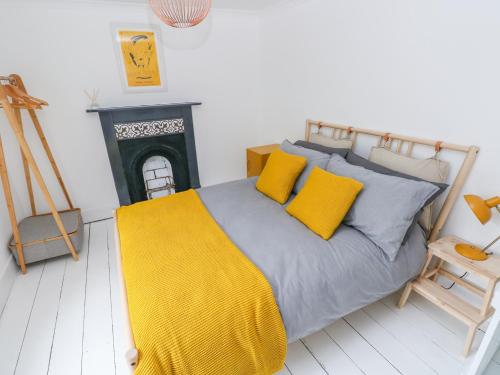 1 dormitorio con cama con almohadas amarillas y chimenea en 5 Park Place, en Tenby