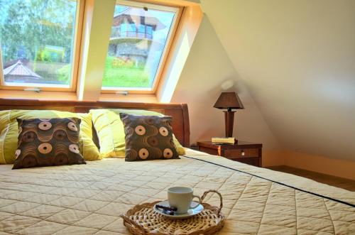 a bed with a tray with a coffee cup on it at Dom nad stawem przy lesie in Burkat