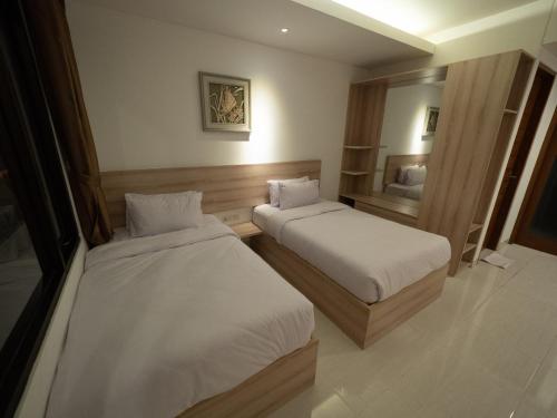 a hotel room with two beds and a mirror at Metta Agara in Kerobokan