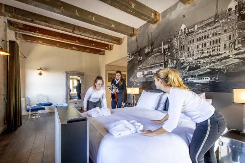 two women standing around a bed in a hotel room at Onderwijshotel De Rooi Pannen Breda in Breda