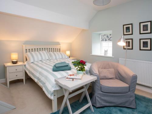 a bedroom with a bed and a chair and a table at Stabl Bach in Llanfaethlu