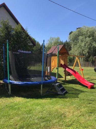 a playground with a slide and a swing set at Apartamentai Karklėje in Karklė
