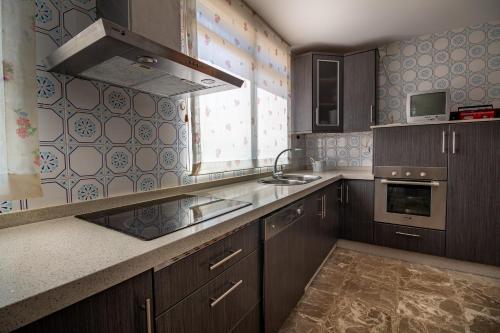 a kitchen with wooden cabinets and a sink and a window at Pensión Casa do Gallo Sarria in Sarria