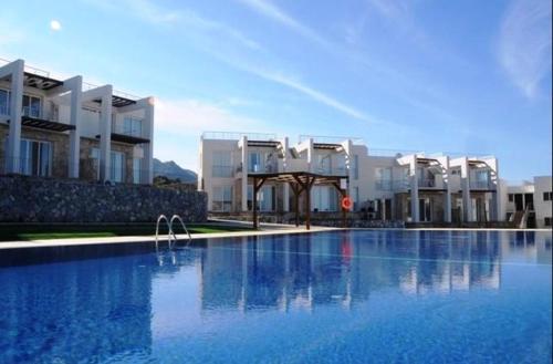 a large swimming pool in front of some buildings at The Seaterra Reserve Penthouse with mountains&seaviews and rooftop terrace in Akanthou