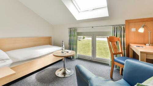 a bedroom with a bed and a desk and a chair at Dorint Parkhotel Siegen in Siegen
