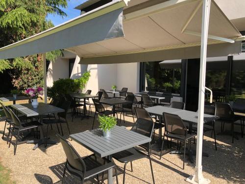 a group of tables and chairs under an umbrella at Logis Hôtel l'Abricotine in Tain-lʼHermitage