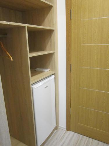 a closet with a white refrigerator and a door at Fehér Hajó Panzió és Vendéglő in Győr